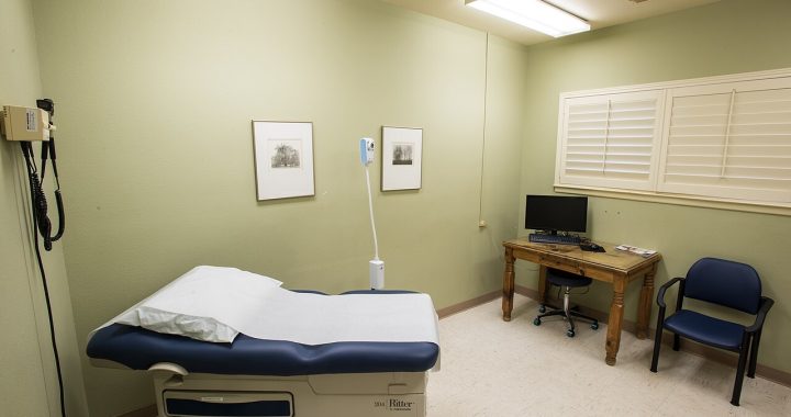 An exam room at a community health center with an exam table, desk and chair