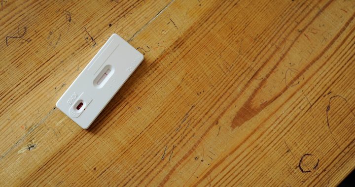 A rapid diagnostic test cassette on a wooden table