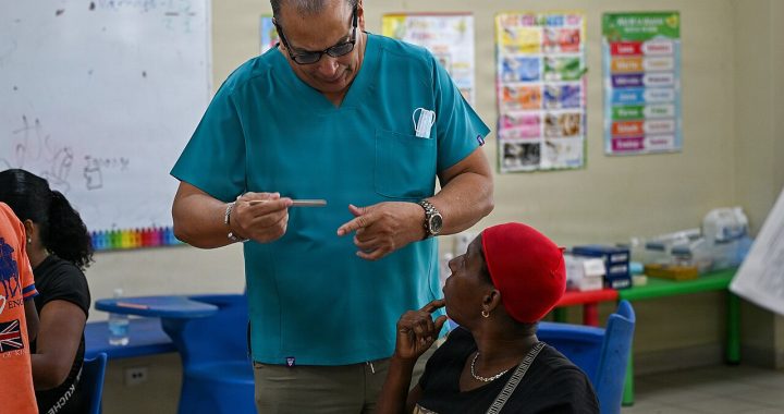 A clinician in teal scrubs talking with a patient in a community clinic